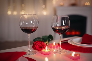 Romantic table setting with wine, rose and candles for Valentine's day dinner indoors