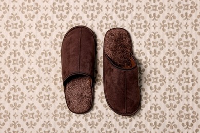 Brown slippers on patterned carpet, top view