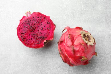 Delicious cut and whole red pitahaya fruits on light grey table, flat lay