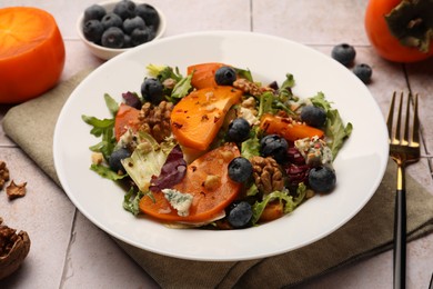 Photo of Delicious persimmon salad and fork on tiled surface