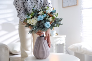 Woman putting beautiful wedding winter bouquet in vase at home, closeup
