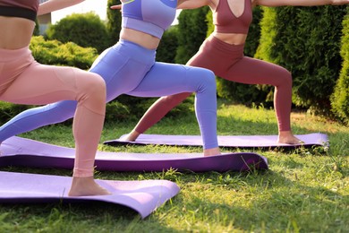 Women practicing yoga on mats outdoors, closeup
