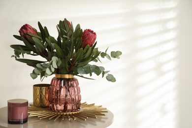 Photo of Vase with bouquet of beautiful Protea flowers on table indoors