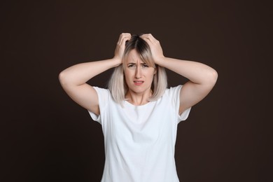 Woman suffering from headache on dark brown background