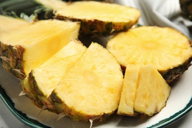 Plate with tasty cut pineapple on table, closeup