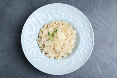 Delicious risotto with cheese on grey table, top view