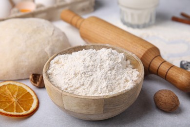 Bowl of flour, rolling pin and ingredients on white table