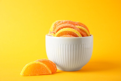 Yummy jelly candies in bowl on orange background
