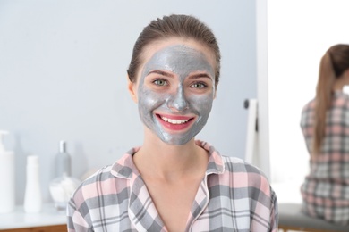 Young woman with cleansing mask on her face in bathroom. Skin care