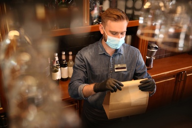 Waiter packing takeout order in restaurant. Food service during coronavirus quarantine