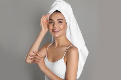 Photo of Beautiful young woman with towel on head against grey background