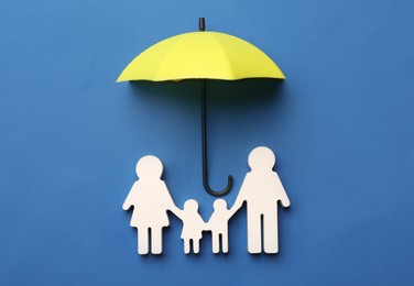 Mini umbrella and family figure on blue background, flat lay