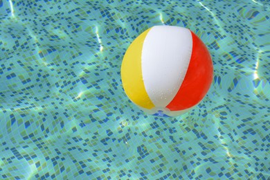 Inflatable beach ball floating in swimming pool, space for text