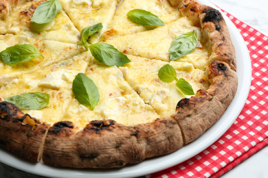 Photo of Delicious hot cheese pizza with basil on table, closeup