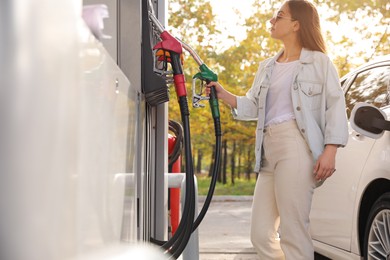 Woman taking fuel pump nozzle at self service gas station