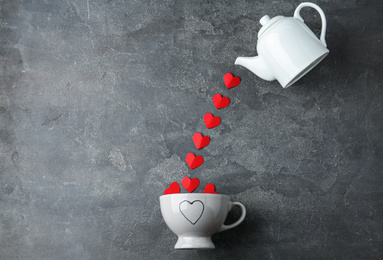 Flat lay composition with teapot, cup and red paper hearts on grey background