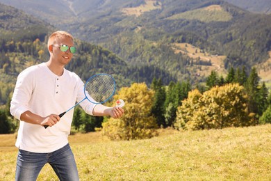Man playing badminton in mountains on sunny day. Space for text