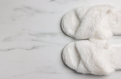 Pair of soft slippers on white marble floor, top view. Space for text