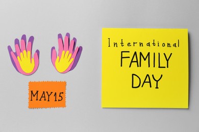 Card with text International Family Day near paper palms on grey background, flat lay