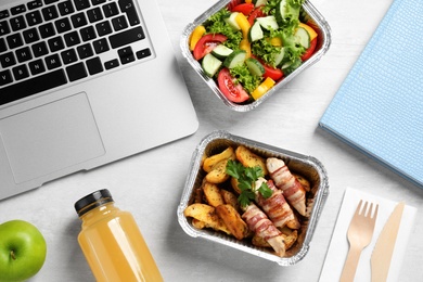 Composition with lunchboxes and laptop on white wooden table, flat lay. Healthy food delivery