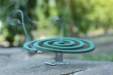 Smouldering insect repellent coil on stone outdoors