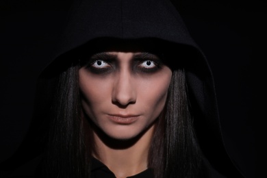 Mysterious witch with spooky eyes on black background