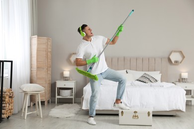 Man with mop singing while cleaning in bedroom