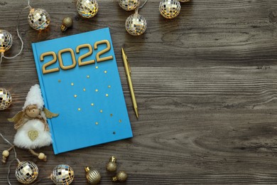 Planner and Christmas decor on wooden background, flat lay with space for text. 2022 New Year aims