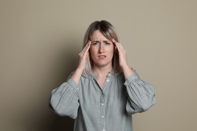 Woman suffering from headache on beige background