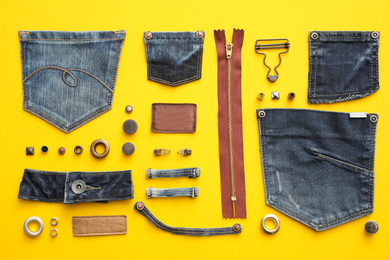 Flat lay composition with garment accessories and cutting details for jeans on yellow background