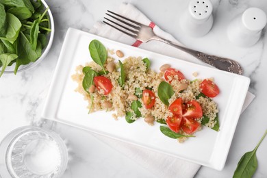 Photo of Delicious quinoa salad with tomatoes, beans and spinach leaves served on white marble table, flat lay