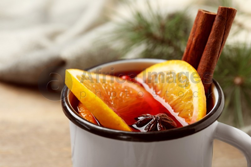 Mug with aromatic mulled wine on wooden table, closeup