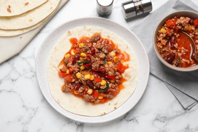 Tasty chili con carne with tortilla on white marble table, flat lay