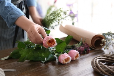 Female florist creating beautiful bouquet at table