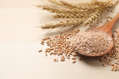 Wheat bran, kernels and spikelets on wooden table, closeup. Space for text