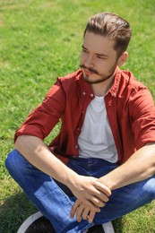 Photo of Handsome man sitting on green grass outdoors