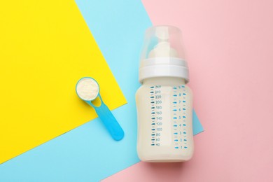 Feeding bottle with infant formula and powder on color background, flat lay