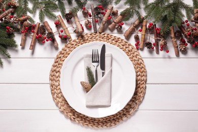 Photo of Plate, cutlery and Christmas decor on white wooden table, flat lay
