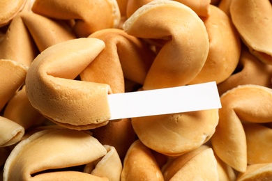 Fortune cookie with prediction on pile of biscuits, closeup