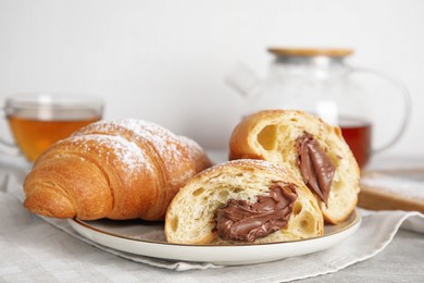 Tasty croissants with chocolate and sugar powder on table, closeup. Space for text