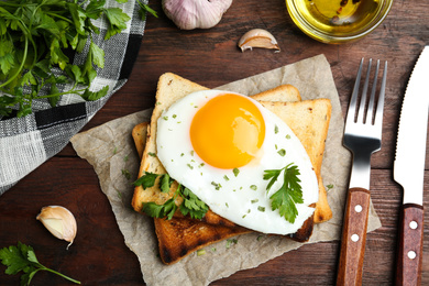 Tasty fried egg with toasts and parsley on wooden table, flat lay