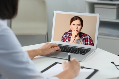 Image of Hotline service. Doctor consulting patient online via laptop indoors