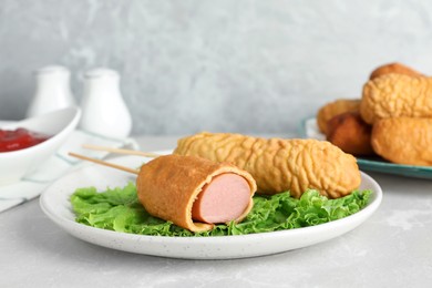Delicious corn dogs with lettuce on light table