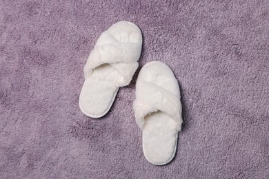 Soft white slippers on fluffy grey carpet, top view