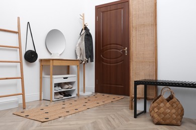 Shelving unit with shoes and accessories near white wall in hall