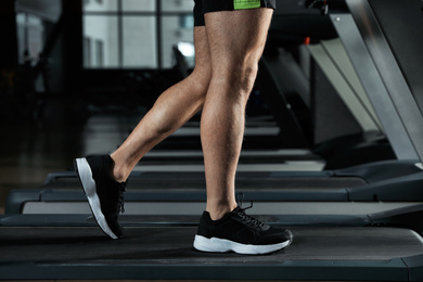 Man working out on treadmill in modern gym, closeup of legs