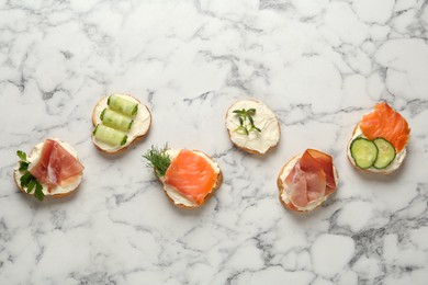 Photo of Delicious sandwiches with cream cheese and other ingredients on white marble table, flat lay
