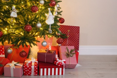 Photo of Pile of gift boxes near Christmas tree indoors