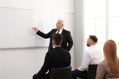Photo of Senior business trainer working with people in office