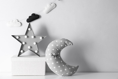 Star shaped lamp, toy moon and box on table, space for text. Interior design